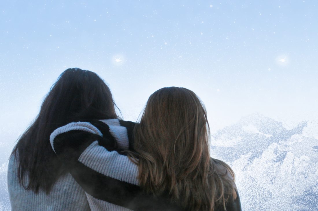 Foto de Laura y Cris con un cielo azul de fondo y unas montañas hechas que parecen magia